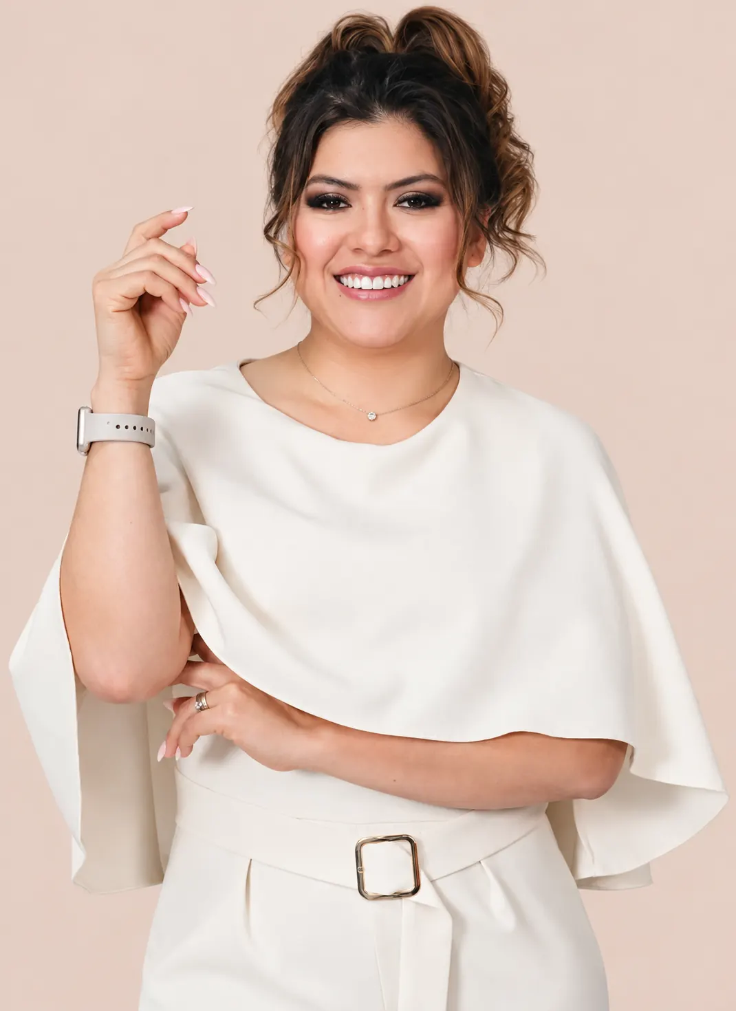 Miri sonriendo con una blusa capa color marfil, con una mano en alto mostrando sus uñas almendra largas.
