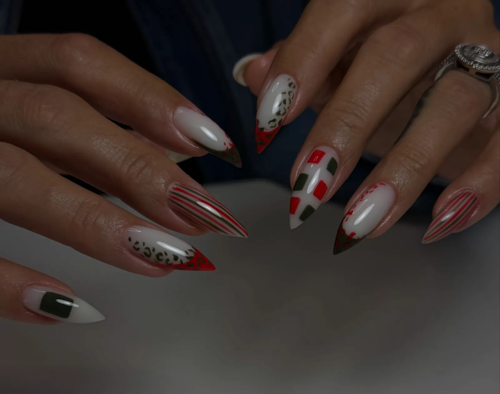 Uñas almendra largas pintadas con diseños en rojo, blanco, verde y azul, rayas y manchas de leopardo.